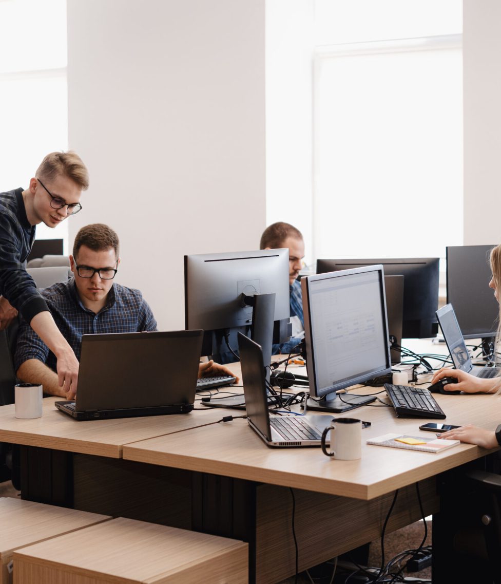 Full concentration at work. Group of young business people working and communicating while sitting at the office desk together with colleagues sitting in the background